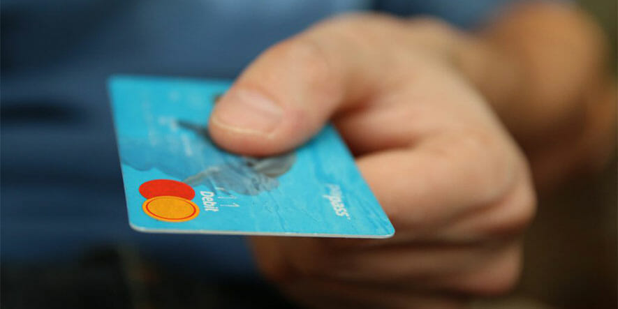 A blue coloured debit card held by a person